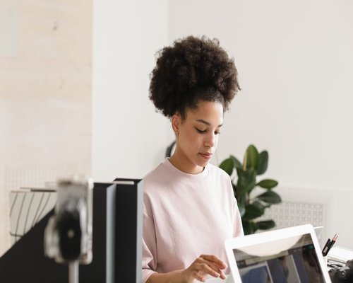 Young woman setting up her ergonomic laptop workspace in a bright apartment in Mexico City