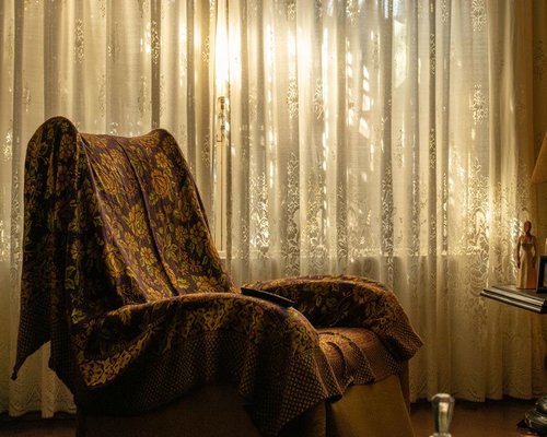 A comfortable armchair next to a large window in Merida, with soft sunlight filtered through curtains