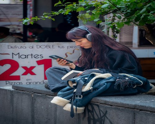 A professional woman listening to a podcast on her phone while commuting on a bus in Mexico City